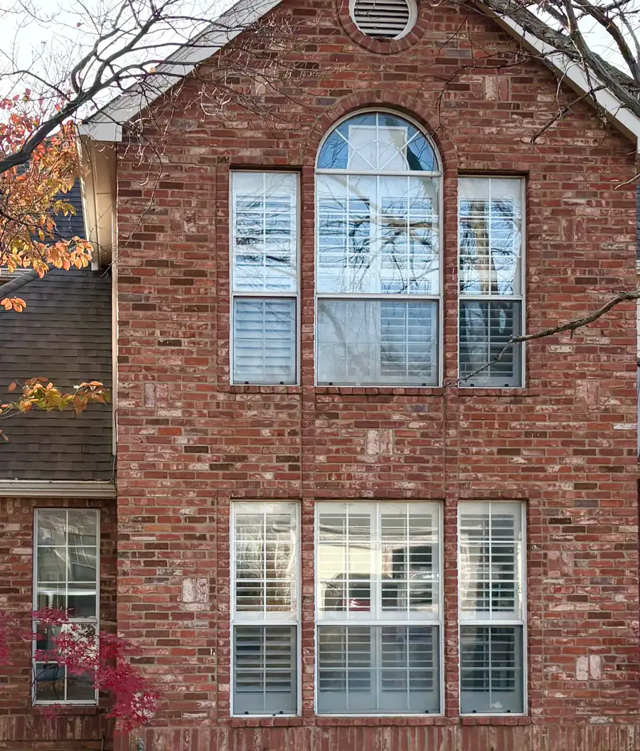 Before: red brick gable with older white windows and interior shutters
