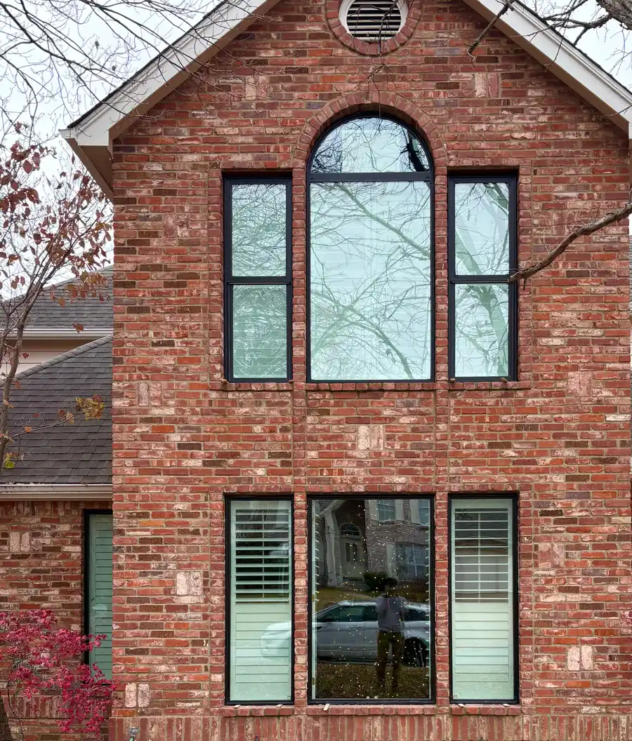 After: the same red brick gable with new black-frame windows