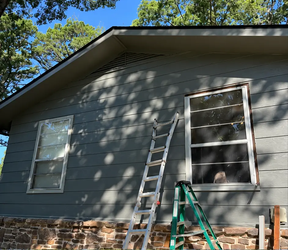 Before: gray siding gable with older white windows during a window replacement