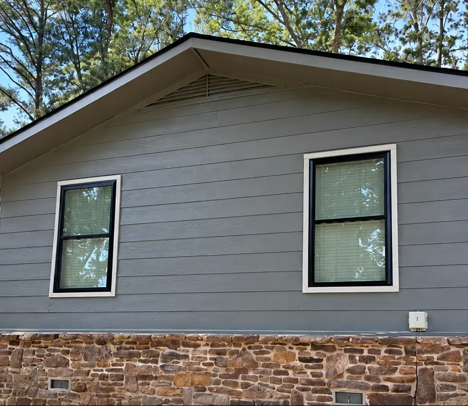 After: the same gray siding gable with new black-frame double-hung windows
