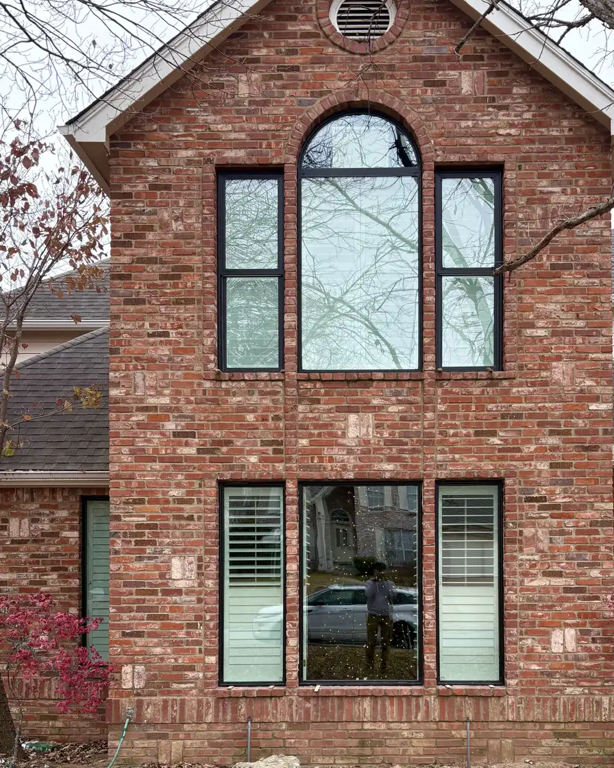 After: the same red brick gable with new black-frame windows