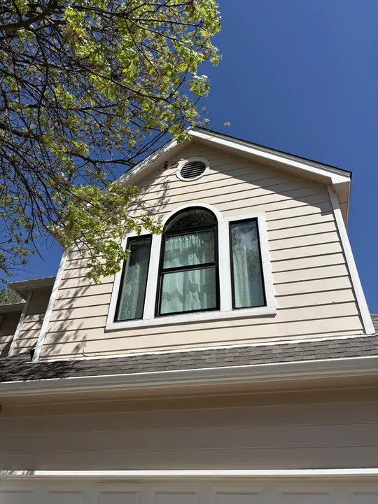 After: tan siding gable with a new black-frame arched window unit