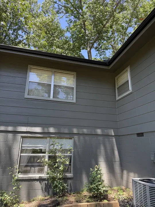 Before: gray-sided two-story home with older white windows