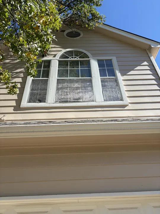 Before: tan siding gable with an older white arched window unit with grids