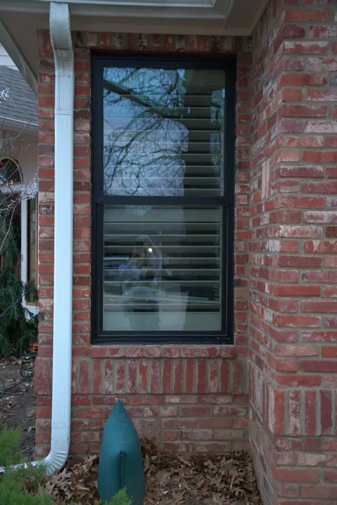 New black-frame double-hung window set in a red brick wall