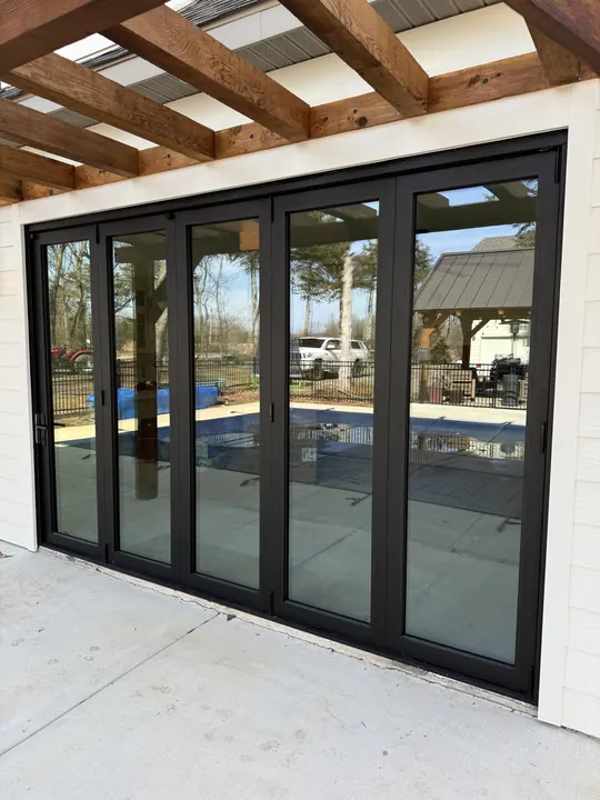 Black folding glass patio doors opening onto a pool