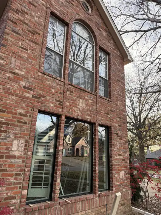 Side view of a red brick home with black-frame windows and an arched window