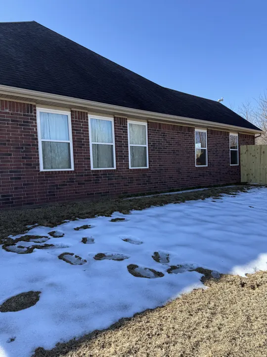 Brick ranch home with white windows in winter snow