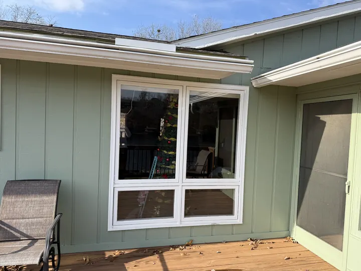 Green-sided home porch with a white window unit beside a screen door