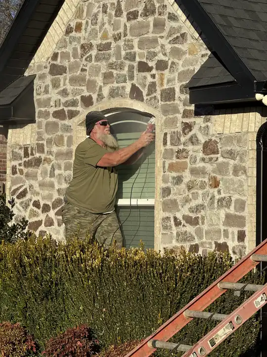 Installer sealing an arched window on a stone home