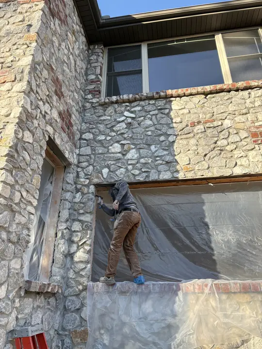 Installer preparing a large window opening in a stone home