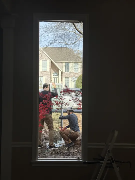Tall new window seen from inside while installers work outside