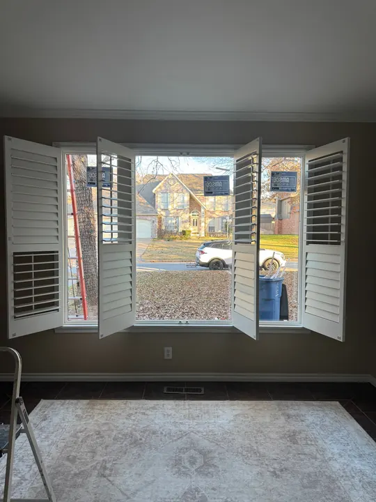 Interior view of a new window framed by open plantation shutters