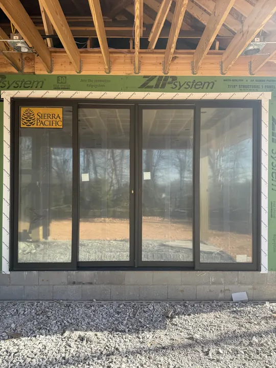 Black sliding glass doors under a covered porch on a home under construction