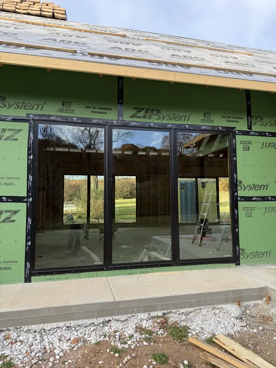 Wall of large black-frame windows and doors on a home under construction