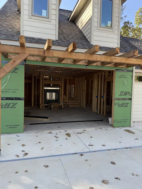 Framed opening for a large glass door under a cedar pergola on a home under construction