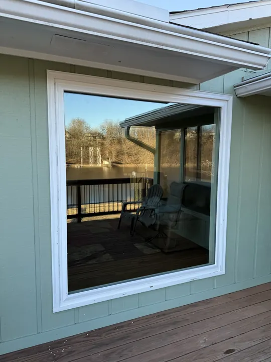 Large white picture window on green siding overlooking a deck