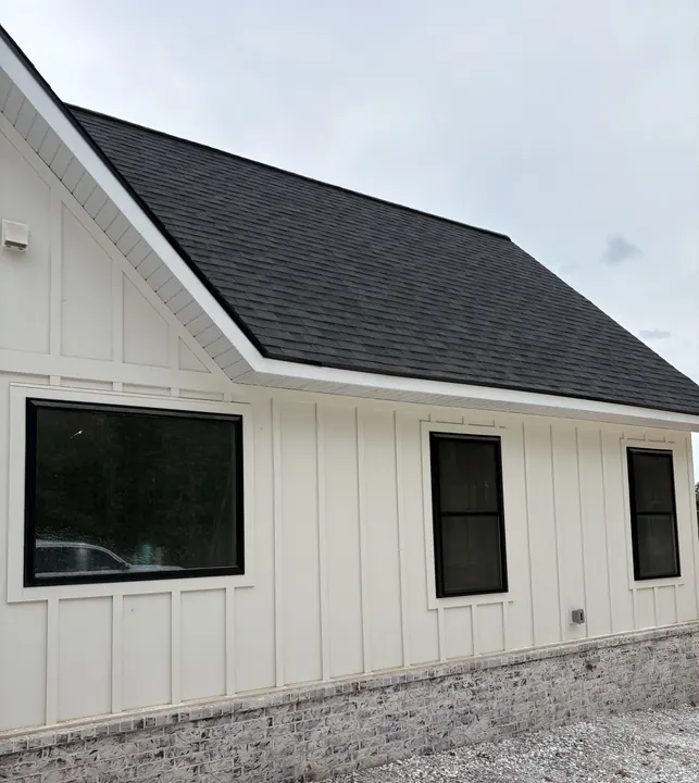White board-and-batten home with large black-frame windows