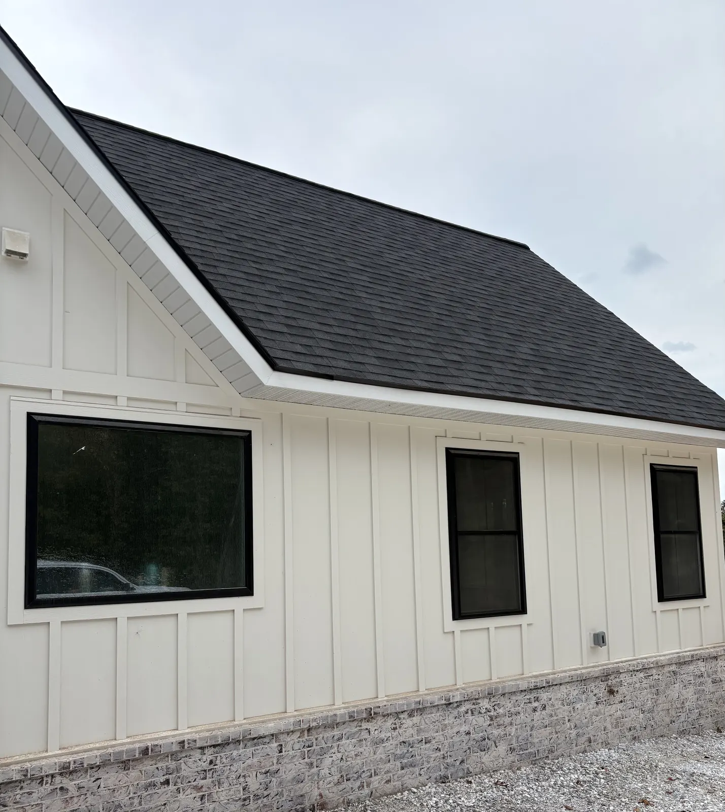 White board-and-batten home with new black-frame windows after installation