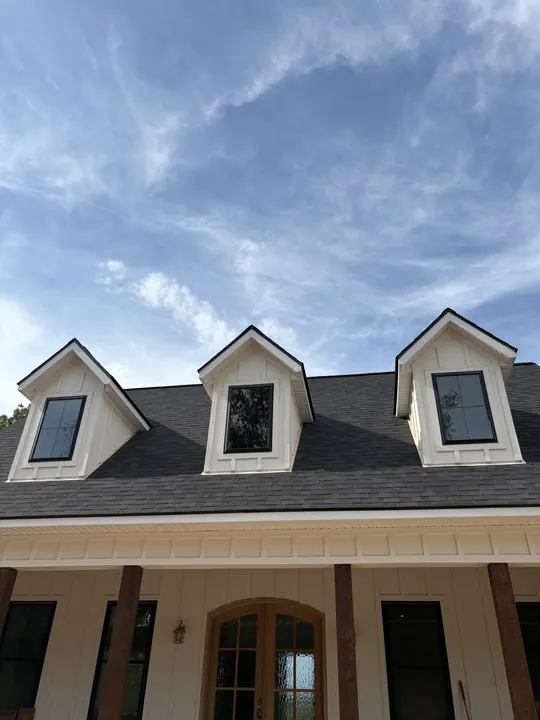 Three white dormers with black-frame windows on a dark shingle roof