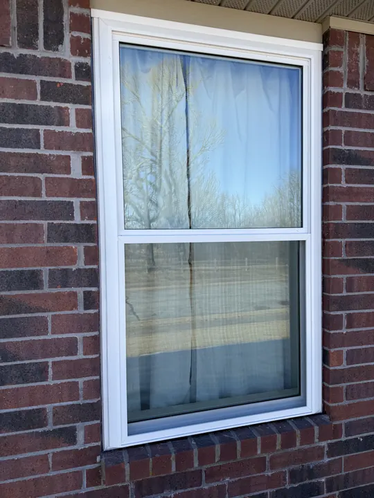 White double-hung window set in a red brick wall